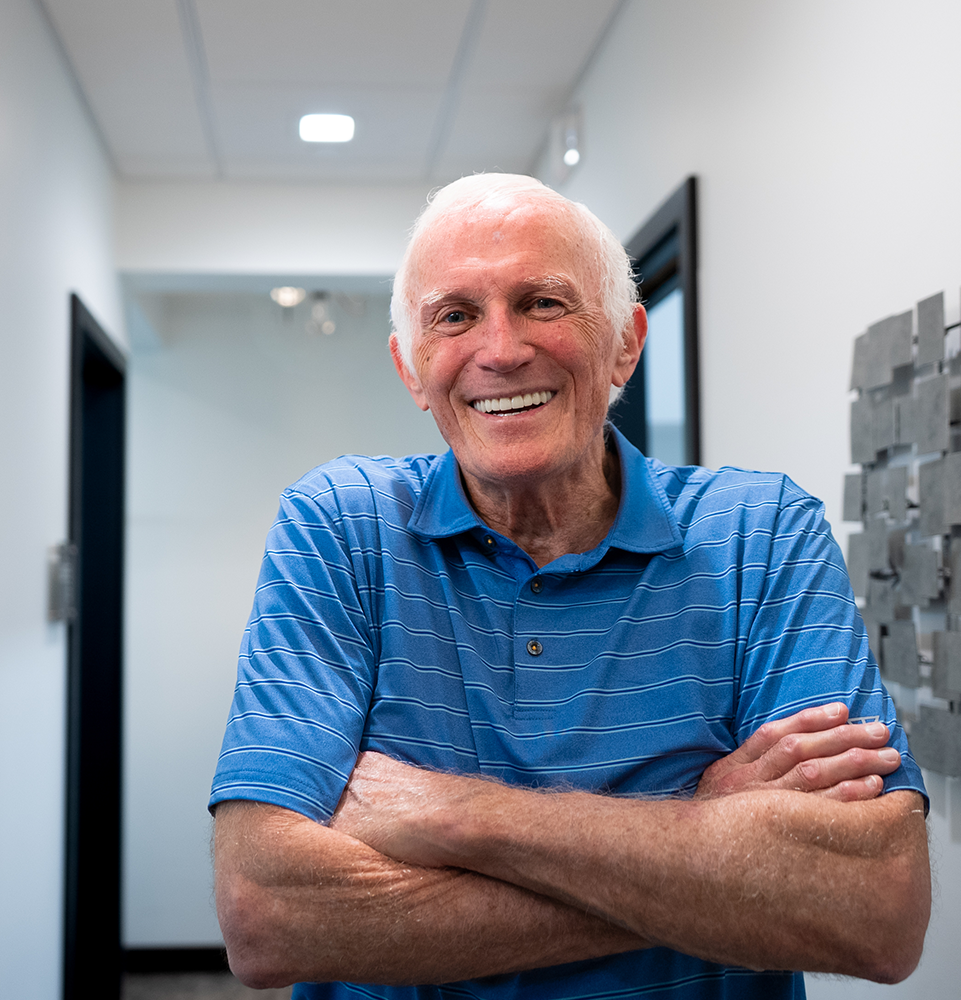 patient in a blue t-shirt smiling in the hallway of the office